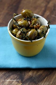 a yellow bowl filled with green olives on top of a blue cloth