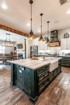 a large kitchen with an island in the middle and two pendant lights hanging from the ceiling