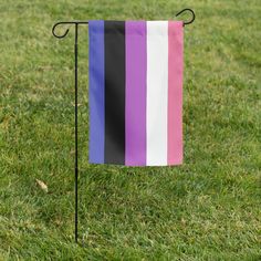 a purple, white and black striped flag on a metal stand in the middle of grass