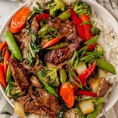 a white bowl filled with beef and vegetables on top of rice covered in broccoli