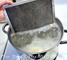 a person holding a strainer over some boiling water