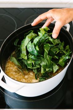 a person is stirring some food in a pot on top of the stove with their hand