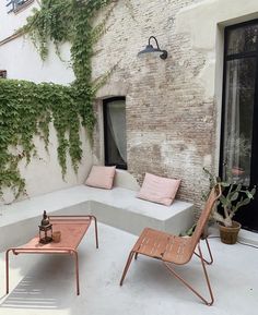 an outdoor seating area with two chairs and a table in front of a brick building