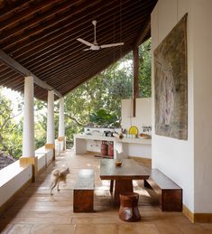 a dog is walking on the floor in front of a table and benches under a wooden roof