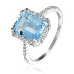 This ring features an emerald-cut blue topaz center surrounded by round brilliant diamonds and a baguette-cut diamond set on each corner with pavé round brilliant diamond side accents in 14K white gold. Total blue topaz weight: 3.54 ct Total diamond weight: 0.23 ct Ring size: 6.5 Baguette Cut Topaz Ring With Diamond Halo Setting, Baguette Cut Topaz Ring With Diamond Halo, Blue Diamond Ring With Baguette Diamonds, Emerald Cut Cubic Zirconia Topaz Ring With Halo Setting, White Gold Topaz Ring With Diamond Accents, Emerald Cut, White Gold Baguette Cut Blue Topaz Ring, Blue Topaz Baguette Cut Ring With Center Stone, Baguette Cut Topaz Ring With Diamond Accents, Blue Diamond Ring With Diamond Accents Emerald Cut