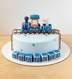 a birthday cake with a blue train on the top and letters that spell it out