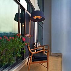 a wooden chair sitting next to a window with a lamp on it's side