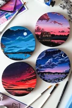 four coasters sitting on top of a table covered in art supplies