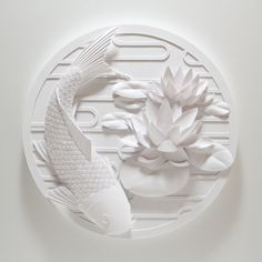 a white paper sculpture with a fish and a lotus on it