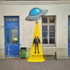 a man standing in front of a yellow cone with a blue and white object on it