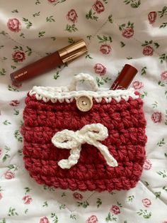 a crocheted purse with lipstick on it and a pen in the bag next to it