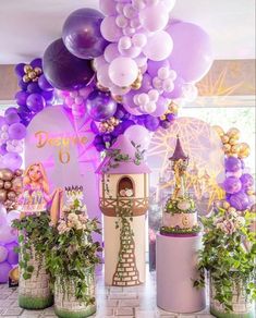 there are many balloons and decorations on the table in front of the cake stand at this princess themed birthday party