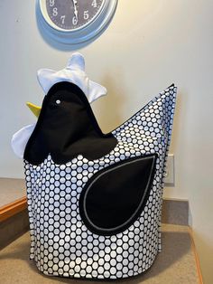 a black and white bird sitting on top of a bag next to a clock in the corner