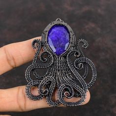 an octopus brooch with a purple stone in it's center, on a hand