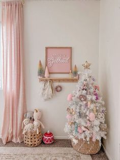 a white christmas tree sitting next to a window in a room with pink drapes