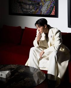 a man sitting on top of a red couch next to a table