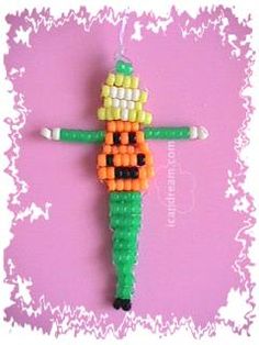 an ornament made to look like a candy corn cob man on a pink background