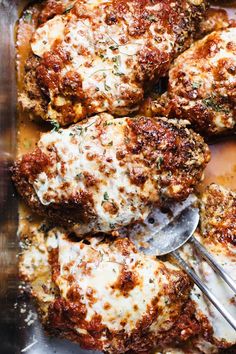 some meatballs covered in cheese and sauce with a spoon