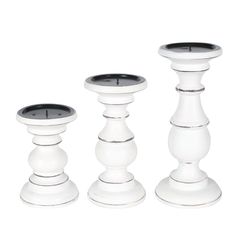 three white candlesticks sitting next to each other