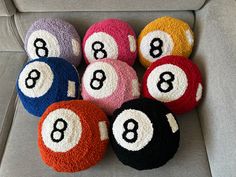 six pool balls with numbers on them sitting on a couch in front of a chair