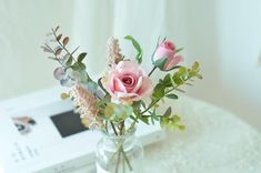 a vase filled with pink flowers on top of a table next to a white box