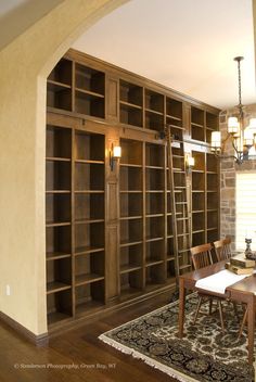 a dining room table and chairs in front of a bookshelf filled with shelves