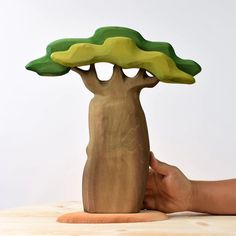 a hand is holding a wooden sculpture with a tree on it