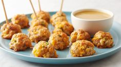 small appetizers are arranged on a blue plate with toothpicks and dipping sauce