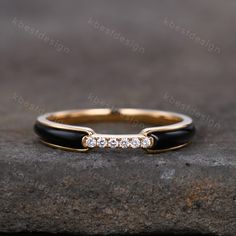 a gold ring with black onyxite and white diamonds, sitting on top of a rock