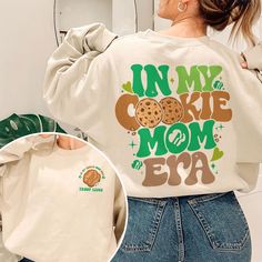 Elevate your Girl Scout style with our exclusive "In My Cookie Mom Era" sweatshirt. Crafted with the perfect blend of comfort and style, this shirt is a must-have for every proud Cookie Scout Mom. The eye-catching design celebrates the joys of being a Scout Mom, making it a perfect gift for Scout Leaders who truly embody the Camp Life spirit. Embrace the spirit of the Cookies Era with our uniquely designed Cookie Dealer shirts, add to your wardrobe today! 💥I. ABOUT PRODUCT - There are many ways to express your personality and wearing our products with eye-catching patterns and meaningful words is one of the ways. Comfortable, casual, and loose-fitting, our products will surely become one of your favorites. Made of cotton, safe and comfortable for anyone. - Using a unique water-based dyein Trendy Letter Print Sweatshirt For Mother's Day, Trendy Cotton Sweatshirt For Mother's Day, Trendy Long Sleeve T-shirt For Mother's Day, Cute Green Sweatshirt With Letter Print, Cute Long Sleeve Tops With Funny Text, Cute Long Sleeve T-shirt For Mother's Day, Cute Long Sleeve Mother's Day T-shirt, Camping Girl, Scout Mom