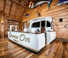 a large white boat sitting on top of a wooden floor next to a wall covered in wood