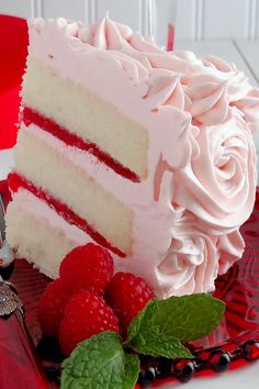 a close up of a cake with raspberries on the side and frosting