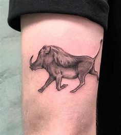 a black and white photo of a bull tattoo on the right thigh, with an outline of a lion running