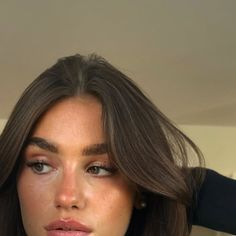 a close up of a woman with long hair and brown eyes looking at the camera