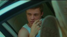 a young man sitting in the back seat of a car talking on a cell phone