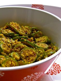 a red bowl filled with green peppers on top of a white and red table cloth