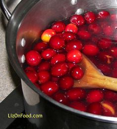 cranberry sauce being stirred in a pot on the stove top with a wooden spoon