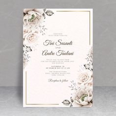 an elegant wedding card with white flowers and greenery is displayed on a gray background