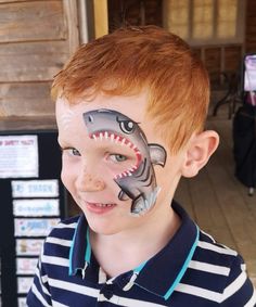 a young boy with his face painted to look like a shark