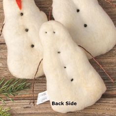 three white rocks sitting on top of a wooden table next to a pine tree branch