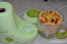 a blender filled with fruit sitting on top of a counter next to a cup