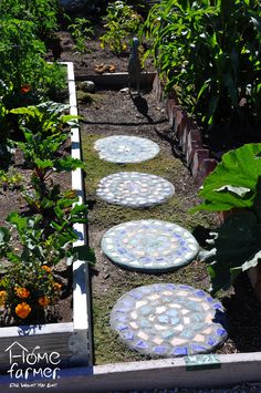 garden path made out of mosaic tiles in the middle of a garden with flowers and plants