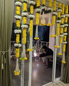 a man sitting in front of a window with yellow flowers hanging from the windowsill