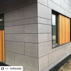 the side of a building with two windows and wood panels on it's sides