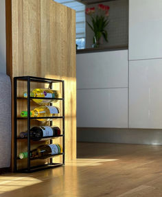 a wine rack with several bottles in it on the floor next to a couch and counter