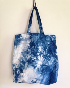 a blue and white tote bag hanging from a hook on the side of a wall