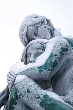 the statue is covered in snow and has its arms around it's head,