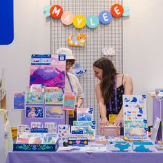 two people standing at a table in front of some cards and magnets on it