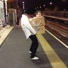 a man holding a cardboard box on top of a train track