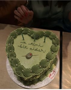 a green heart shaped cake with writing on it